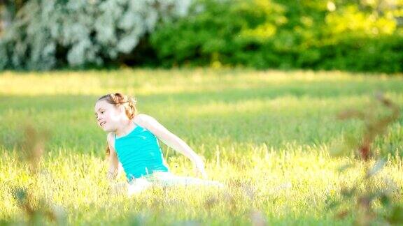 可爱的小女孩坐在草地上在夏天的公园里玩耍