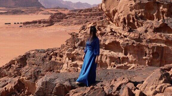 身着蓝色衣服的女人凝视着瓦迪鲁姆沙漠的风景