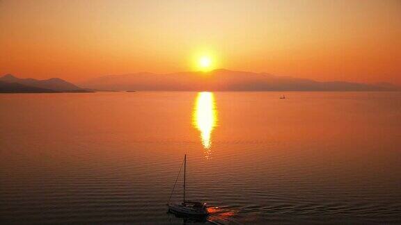希腊爱奥尼亚海岸的日落明亮的阳光远处的陆地漂浮的小船水中的倒影