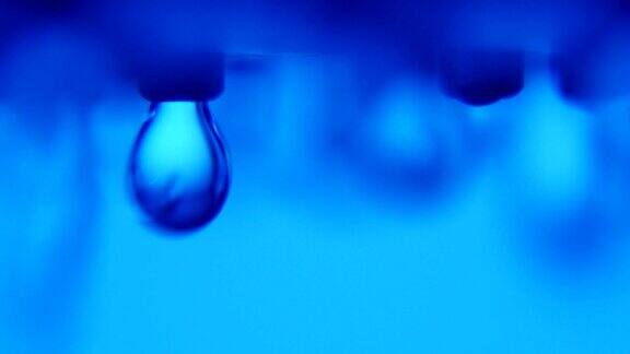在一间现代的蓝色浴室里令人眼花缭乱的水滴从金属射流上落下