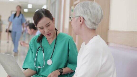 医院保健医生仔细地向老年患者讲解充电器上的医学检查结果年轻的亚洲女护士护理人员支持与老年妇女病人交谈帮助解决问题