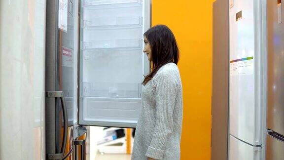 一名年轻女子在家电商店挑选一台电冰箱