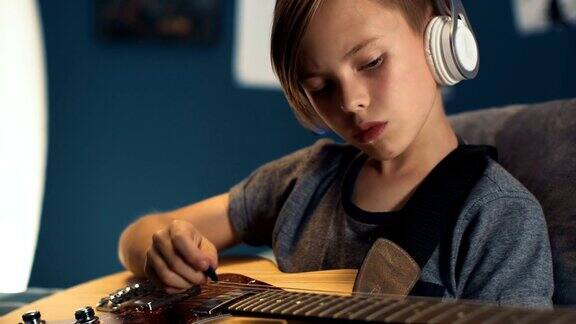 男孩戴着耳机和吉他学习歌曲