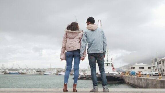 一段4k视频记录了一对年轻夫妇站在港口码头欣赏风景的画面