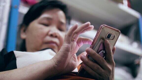 使用智能手机的亚洲老年妇女
