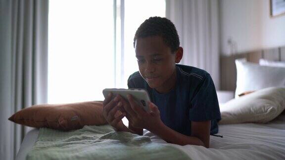 男孩躺在床上用智能手机看视频