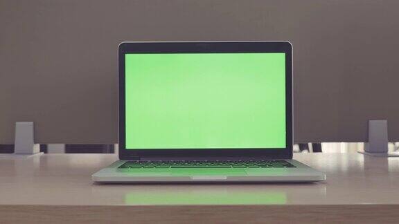 在办公室里的笔记本电脑显示绿色色度键屏幕的场景拍摄技术在背景中技术背景