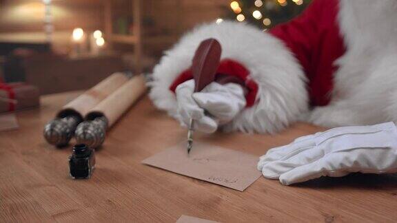 戴着白手套的圣诞老人用钢笔在桌上的信封上签了名
