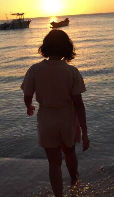 日落时分在海滩上散步的女人