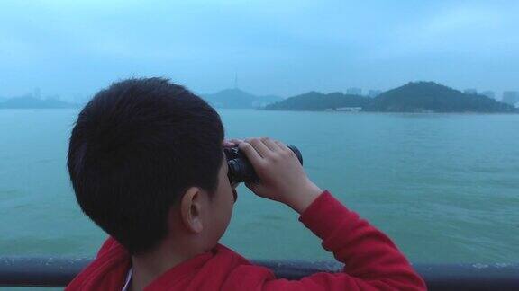 小男孩在游船上用双筒望远镜四处张望