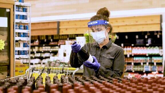 成熟的女人在超市买酒时戴着防护口罩外科手套和面罩