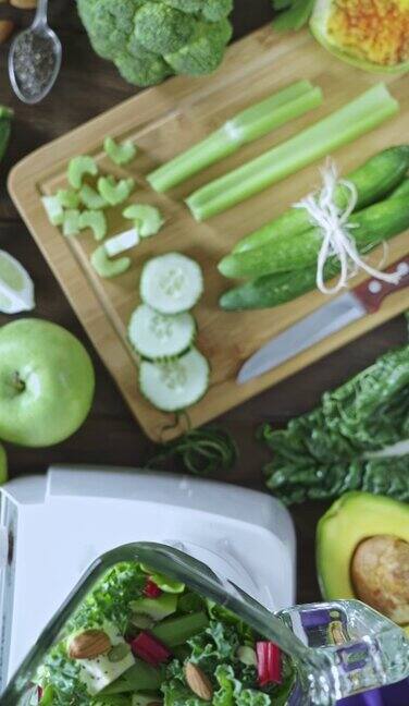 饮食概念:正下方的平移视图拍摄的妇女手切蔬菜为排毒沙冰切菜板和搅拌机放在厨房的桌子上