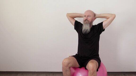 男子坐在健身球上做静态颈椎运动