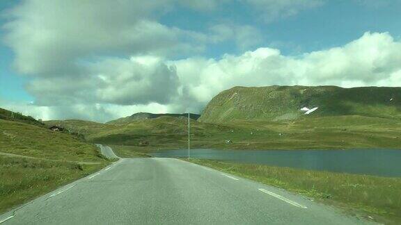 在挪威的公路上开车挪威美丽的风景湖泊和道路挪威山区的一条路
