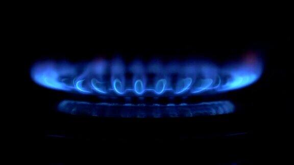 煤气开关打开出现蓝色火焰黑色背景上的煤气炉