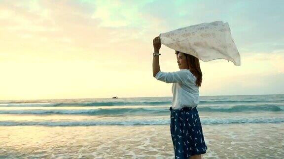 年轻快乐的女人戴着围巾在海滩上