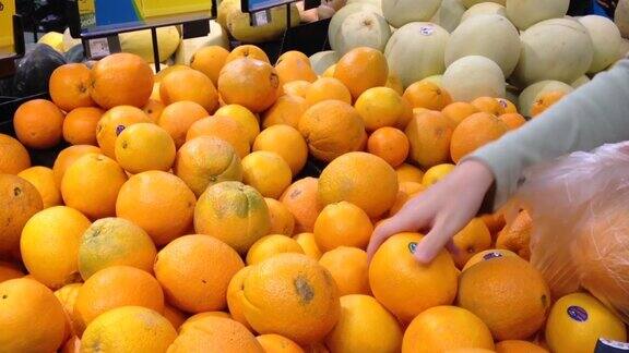 在杂货店挑选新鲜橙子的女人