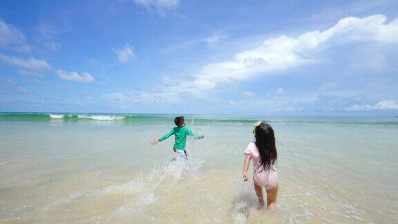 亚洲小男孩和小女孩在夏天阳光灿烂的日子里在海滩上玩海水