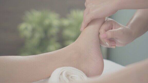 专业治疗师给传统泰国腿和脚部按摩在水疗中心的一个女人