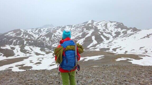 成功的女登山者在冬季的高海拔雪山山顶上观看风景