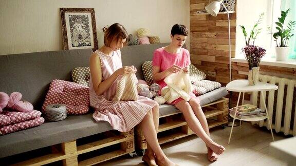 两个女朋友坐在沙发上聊天在家具上织毛线衣服
