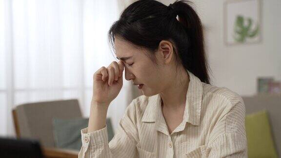 特写镜头:一位过度劳累的亚洲女企业家在家里用笔记本电脑工作时闭上了她痛苦干燥的眼睛感到非常不舒服