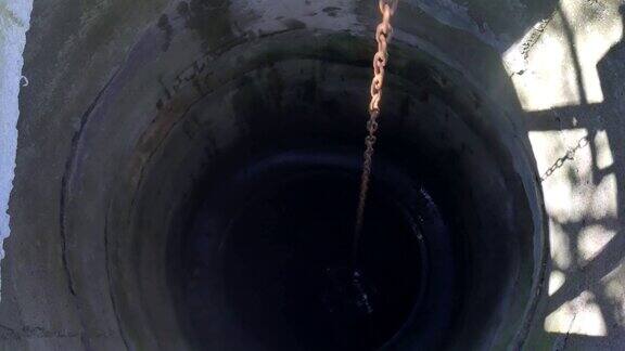 人们把铁链和水桶丢进乡下的井里打水