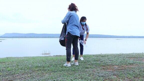 为了保护环境两位亚洲妇女在湖上捡拾塑料瓶