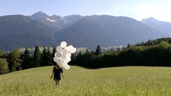 女孩带着白色气球走下高山