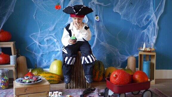 可爱的小男孩穿着海盗万圣节服装在家吃巧克力松饼