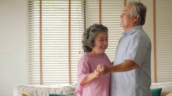 快乐的老年情侣在家里用慢镜头跳舞