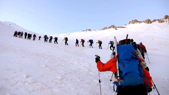 冬季高山登山者正在观看登山队在山顶的攀登