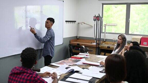 亚裔马来男讲师在教室里用白板给他的学生讲授珠宝设计课程