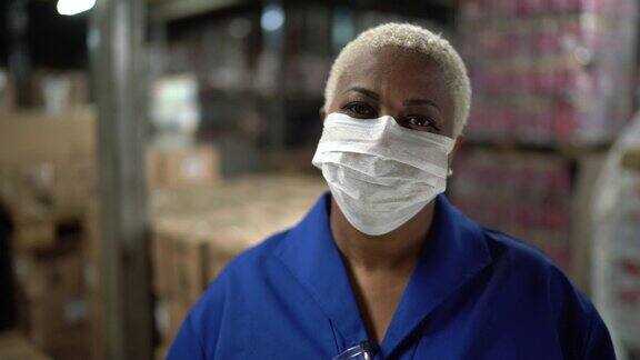 在仓库工业中工作的成熟妇女戴口罩的肖像