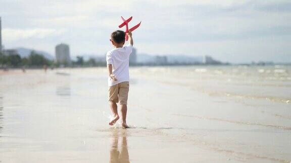 亚洲小孩在海滩上玩纸板飞机