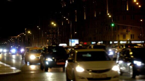 出租车经过夜晚的城市灯光十字路口塞车市中心一片模糊车头灯和led灯反射在道路上