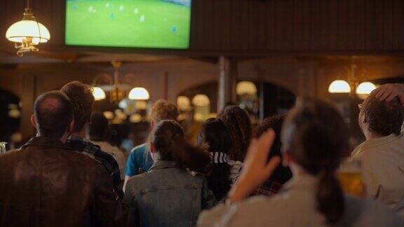 一群朋友在体育酒吧看电视直播的足球比赛兴奋的球迷欢呼和喊叫当球队进球并赢得足球世界杯时年轻人庆祝