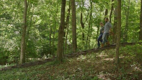 慢动作拍摄的一个白人男人和女人在他们的四十多岁一起走下山的森林在一个阳光明媚的一天在田纳西州