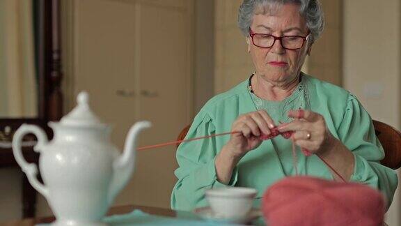 高级妇女编织在家里茶时间