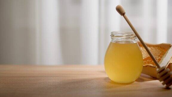 蜂蜜的背景玻璃瓶里装着甜蜂蜜木桌上放着蜂蜜匙