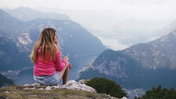 女人坐在山顶凝视着美丽的风景