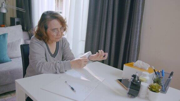 一位年长的妇女使用腕表在家测量自己的血压