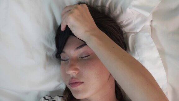 平静的年轻女子在床上休息时戴着睡眠面具从以上观点