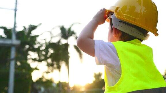 一个男孩戴着安全头盔作为一名工程师站在他的父母面前玩耍