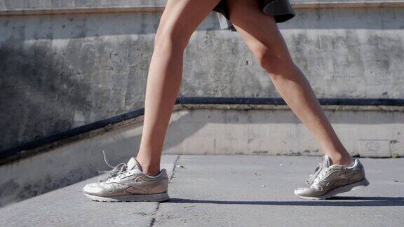 近距离的女人的腿在运动鞋女孩下了城市的楼梯慢动作
