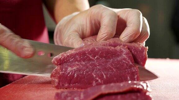 厨师用刀在红板上切生肉特写慢动作