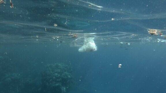 塑料和其他垃圾慢慢漂浮在蓝色的水面上接近珊瑚礁海洋的大规模污染