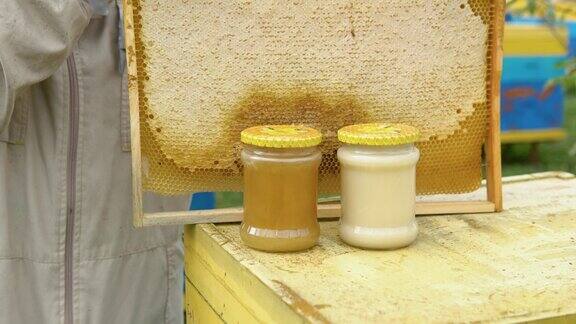 近距离的养蜂人与蜂窝框架和罐蜂蜜养蜂养蜂人收获蜂蜜