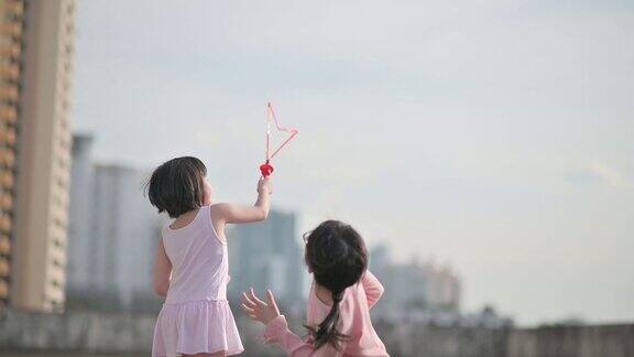 亚洲华人的兄弟姐妹年轻的女孩妹妹玩泡泡在晚上日落户外