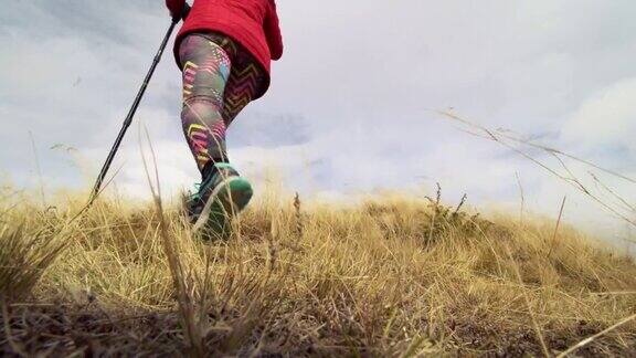 在山间草地上徒步旅行的女孩普通运动鞋和腿在草地上的低角度视图健康的户外健身生活方式